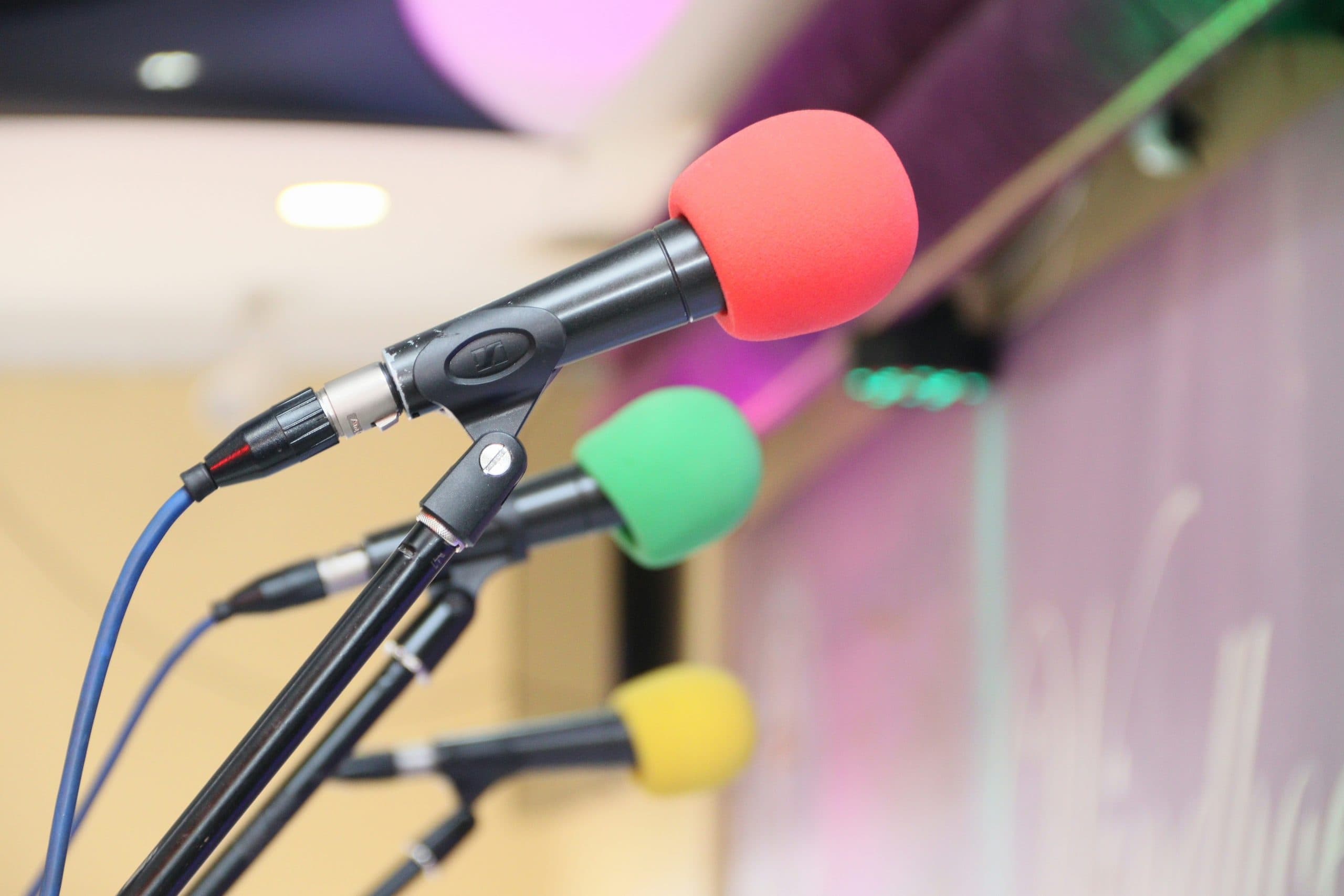 Three microphones on their stand: one red, one green and one yellow.