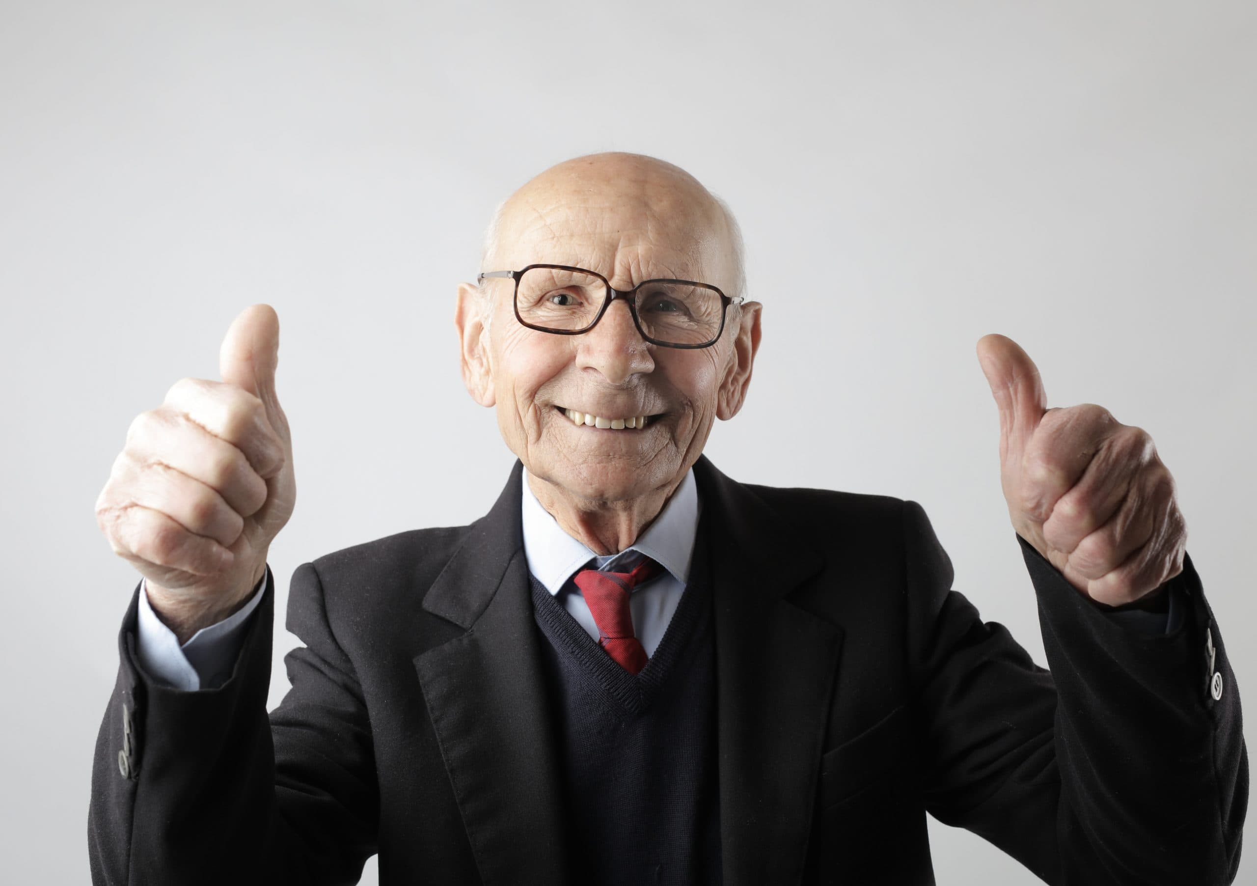 An old man smiling and having his two thumbs up