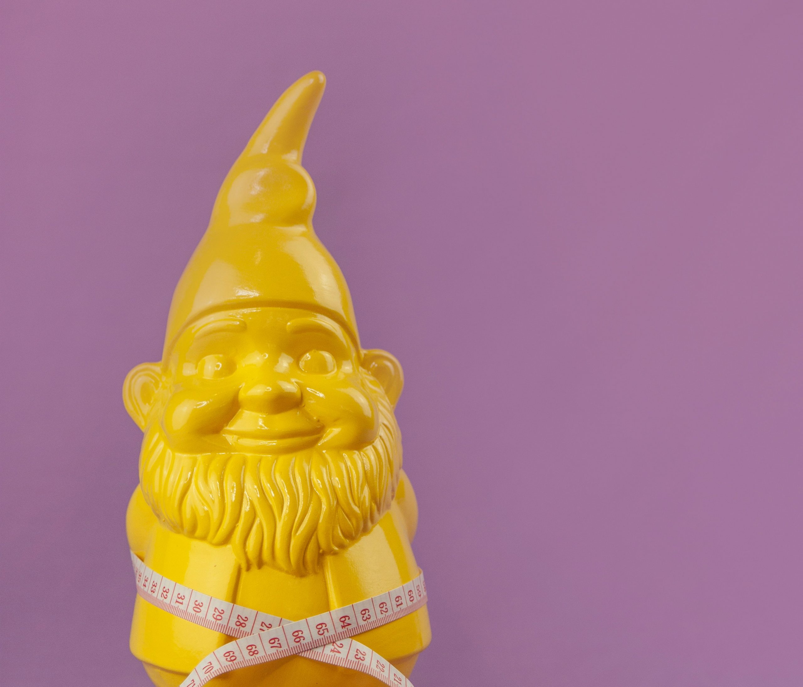 A yellow garden gnome on a pink background