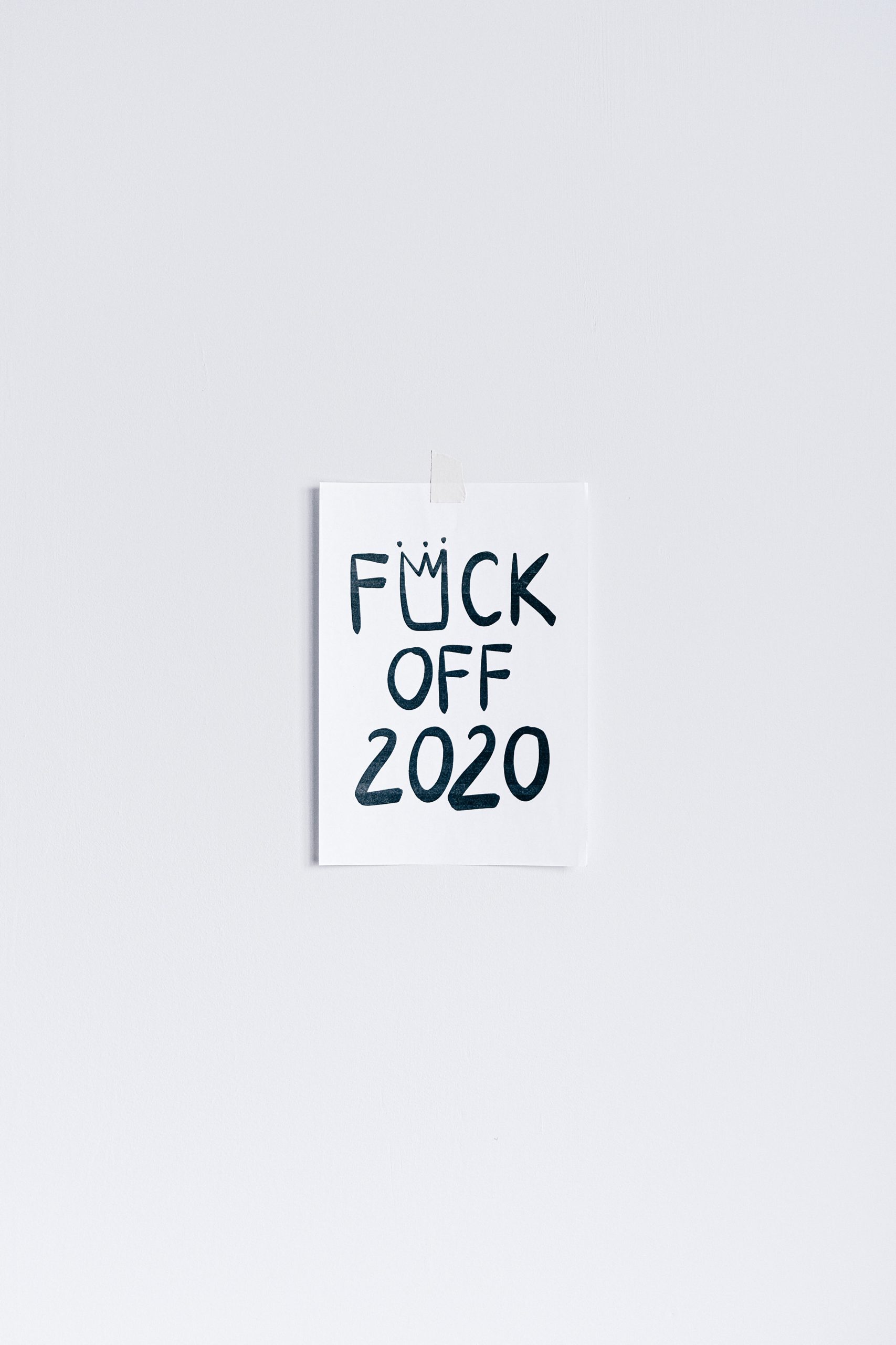 A piece of paper written "fuck off 2020" hanging on a wall